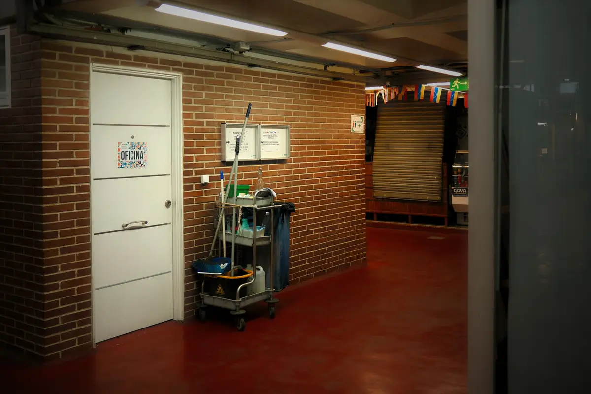 A janitorial cleaning cart parked by an office door in a bright commercial hallway